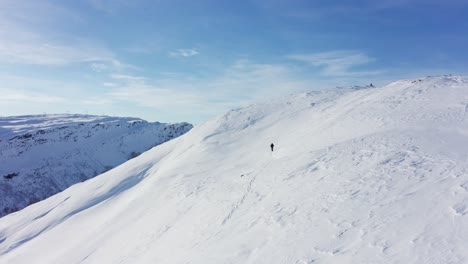 Aerial-shot-slowly-overtaking-person-walking-on-ski-uphill,-beautiful-snow-covered-Landscape