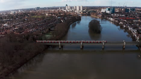 Cinematic-rotating-drone-shot-of-London-district-line-train-on-Kew-railway-bridge