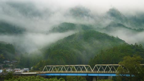 Statische-Aufladung,-Brücke-Vor-Einem-Bewaldeten,-In-Nebel-Gehüllten-Hügel,-Japan