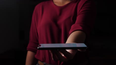 Corporate-woman-holding-latest-smartphone-in-the-dark
