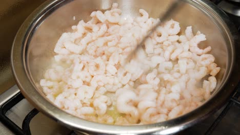 Spreading-small-fresh-shrimps-with-black-spatula-in-hot-pot
