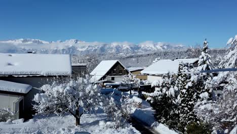 Footage-of-houses-full-of-snow-with-alps-mountain-and-blue-sky