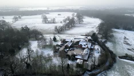 Large-house-Essex,-UK-Snow-covered-landscape-winter-aerial-4k