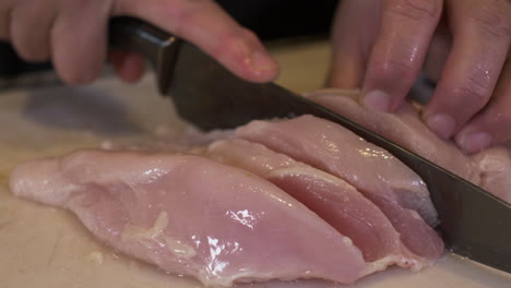 Close-Up-Of-Female-Hands-Slicing-Raw-Chicken-Meat-With-Knife-On-Chopping-Board