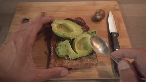 Person-Smashing-Fresh-Avocado-On-Toasted-Bread-By-Teaspoon