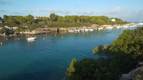 Ship-that-leaves-in-the-morning-between-the-navigation-buoys-in-the-cala-Santandra-cove-in-Menorca,-Spain