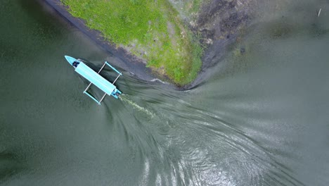 Aerial-footage-of-a-blue-motor-boat-travelling-down-a-narrow-lake