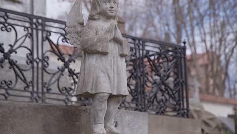 Statue-Des-Kleinen-Engels-Auf-Sockel-Vor-Grabstein-Auf-Dem-Friedhof-Von-Bernardinai