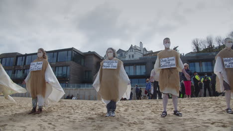 Demonstrators-stand-in-line-on-beach-to-protest-against-Ecological-Downfall-of-Carbis-Bay-Hotel,-Cornwall