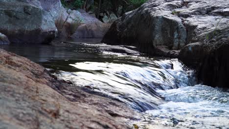 Pristine-scenery-of-silky-shining-stream-calmly-flowing-and-rocky-banks
