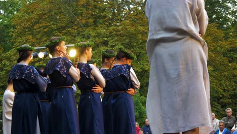 Bailarinas-Caucásicas-Adultas-Con-Trajes-Folclóricos-Azules-Tradicionales-Actúan-En-Un-Espectáculo-De-Danza-Al-Aire-Libre,-Tarde-Soleada-De-Verano,-Feliz,-Cultura-Nacional-Letona,-Toma-De-Mano-Mediana