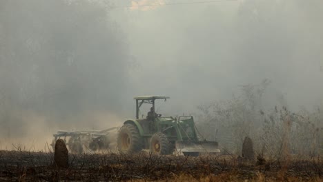 Agricultor-Conduciendo-Su-Tractor-A-Través-De-Nubes-De-Humo-De-Un-Incendio-Forestal-En-Llamas-En-El-Amazonas