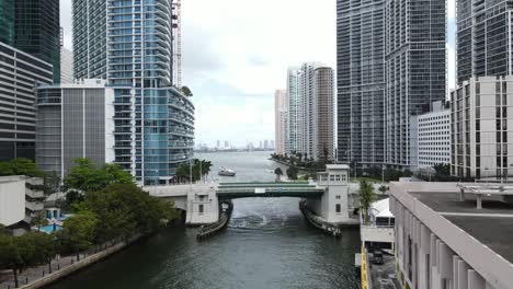 Aerial-view-of-a-mega-yacht-approaching-the-Miami-River-before-the-Brickell-Avenue-Bridge-and-beautiful-downtown-Miami,-Florida,-USA