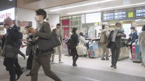 Viajeros-De-La-Población-Que-Usan-Máscara-Médica-En-Las-Puertas-De-La-Estación-De-Tren-En-Tokio,-Japón
