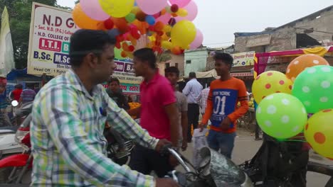Vorbeifahren-An-Einem-Markt-Mit-Menschen,-Die-Sich-Mit-Luftballons-Und-Motorrädern-In-Indien-Versammeln