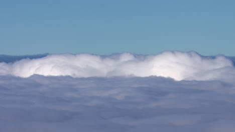 Landschaftsaufnahme-über-Tief-Liegenden-Weißen,-Flauschigen-Wolken,-Die-Die-Rollenden-Wolken-Und-Den-Strahlend-Blauen-Himmel-Darüber-Zeigt
