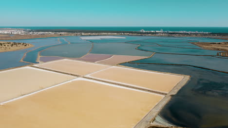 Aerial-flyover-colorful-salt-lakes-in-Portugal-with-Atlantic-Ocean-in-background---Europe-during-summer-day