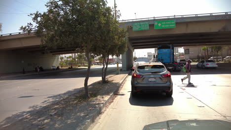 Tagsüber-Verkehr-In-Einer-Belebten-Straße-In-Tijuana,-Mexiko-Mit-Mann-Beim-Überqueren