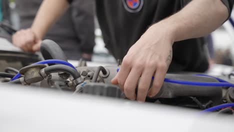 Hands-checking-cables-and-hoses-of-a-car-engine-in-slow-mo