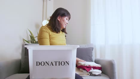 Portrait-of-Woman-selecting-clothes-for-donation-and-putting-in-box