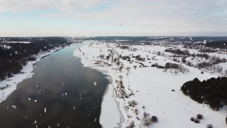 Winter-wonderland-and-Nemunas-river-during-snowfall,-aerial-drone-view