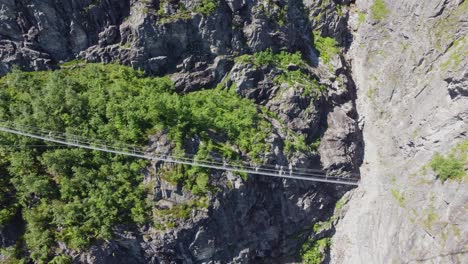 Via-Ferrata-bridge-crossing-deep-gorge-canyon-in-Loen-Norway---Dangerous-suspension-bridge-enroute-to-mountain-Hoven---Aerial-with-person-walking-on-bridge-in-beginning-of-clip