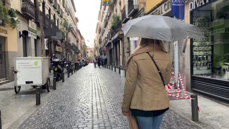 4K-clip-of-a-young-girl-walking-peacefully-in-the-middle-of-the-centre-of-Madrid-city-on-a-rainy-day