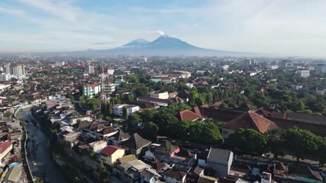 Vista-Aérea,-Vista-De-La-Ciudad-De-Yogyakarta,-Que-Está-Llena-De-Casas,-Ríos-Y-Volcanes-Visibles-Cuando-El-Clima-Está-Despejado