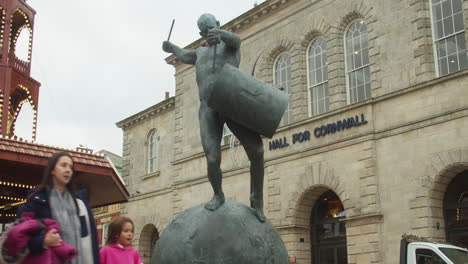 Tim-Shaws-Bildhauer-„der-Schlagzeuger“-Mit-Der-Halle-Des-Cornwall-Gebäudes-Und-Menschen,-Die-An-Der-Statue-In-Truro,-Cornwall,-Vorbeigehen