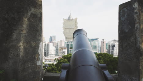 Macau---Kanone-Auf-Den-Stadtmauern-Des-Monte-Forte-Mit-Dem-Grand-Lisboa-Hotel-In-Der-Ferne