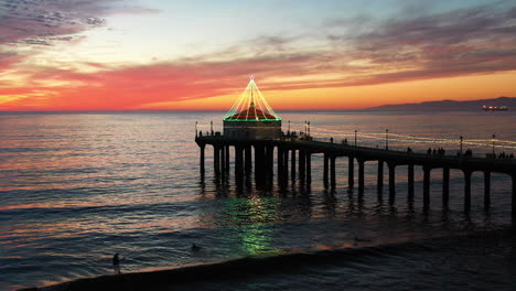 Luftaufnahme-Des-Manhattan-Beach-Piers,-Der-Bei-Sonnenuntergang-In-Weihnachtsbeleuchtung-Leuchtet,-Kalifornien
