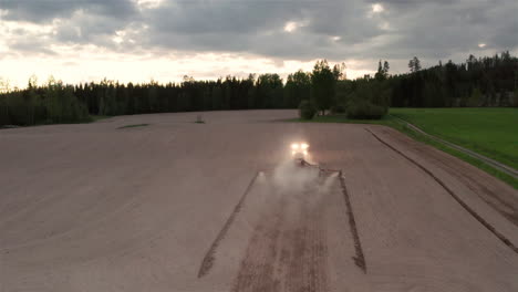 AERIAL---Tractor-sowing-seeds-at-dusk,-Hedemora,-Sweden,-wide-shot-forward