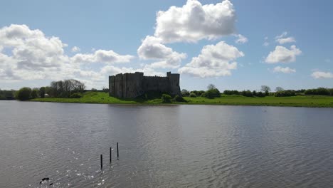 Drone-flying-over-river-with-Carew-Castle-in-background,-Wales