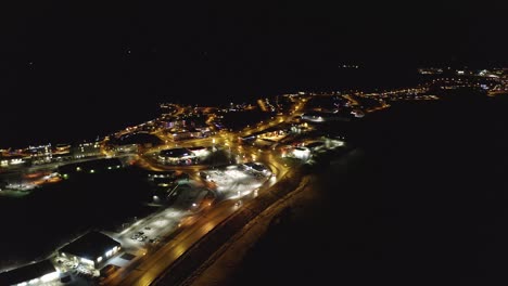 Aerial-orbit-shot-showing-Borgarnes-Town-in-West-Iceland-at-night-with-driving-cars-at-road-and-lighting-buildings