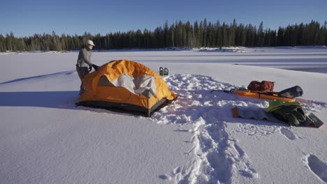 Mann-Baut-Beim-Zelten-Ein-Orangefarbenes-Zelt-Im-Schnee-Auf