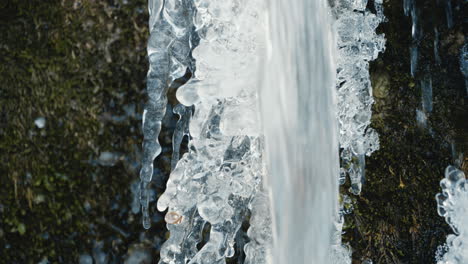 Kleiner-Wasserfall-Vor-Einem-Eiszapfen-In-Einem-Zugefrorenen-Fluss-Im-Winter,-Nahaufnahme,-Echtzeit
