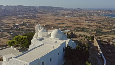Paros-Greece-Aerial-v10-cinematic-drone-reverse-flyover-hilltop-st-antonios-monastery-with-beautiful-white-facade-overlooking-at-the-vast-island-landscape---September-2021
