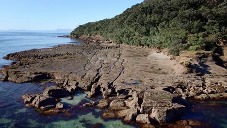 Luftanflug-Auf-Gemeißelte-Und-Erodierte-Felsformationen-Am-Ufer-Der-Ziegeninsel-An-Einem-Strahlend-Sonnigen-Tag,-Neuseeland