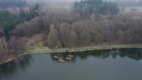 Luftaufnahme-Eines-Sees-Im-Herbstwald-Mit-Einem-Weg,-Durch-Den-Menschen-Gehen