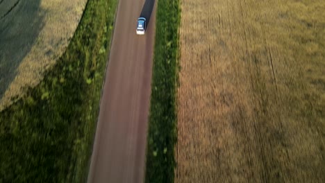 Aerial-vertical-shot-of-minivan-driving-along-dirt-road-in-rural-Canada