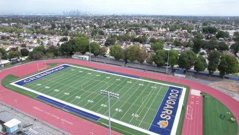 Crenshaw-high-school-football,-empty-stadium,-aerial-rising-on-cloudy-day