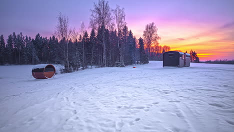 Beautiful-day-to-night-time-lapse-of-snowy-winter-landscape-and-colorful-sky-during-sunset---Fir-trees,barell-sauna-and-wooden-cottage-during-vacation-in-Northern-Europe