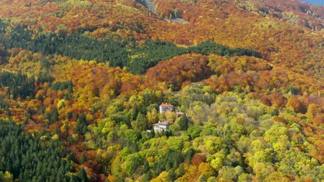 houses-on-a-mountain-slope-covered-with-autumn-foliage,-aerial-tilt-up