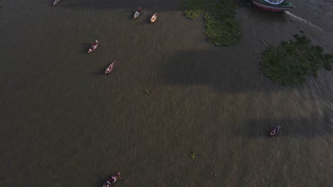 Luftaufnahme-Von-Schiffen-Und-Booten,-Die-Vorbeifahren,-Um-Das-Meer-Zu-Erreichen,-Um-Fische-Zu-Fangen,-Und-Einer-überfüllten-Stadt-Im-Alten-Dhaka,-Bangladesch-Im-Hintergrund-An-Einem-Schönen-Morgen