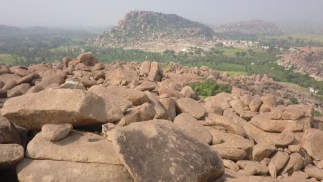 One-male-tourist-stands-on-massive-granite-boulder-in-Hampi,-India