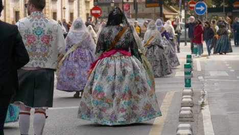 Rear-view-shot-of-Spanish-women-in-traditional-Falla-dresses-walk-down-the-street-during-the-Fallas-festival-in-Valencia