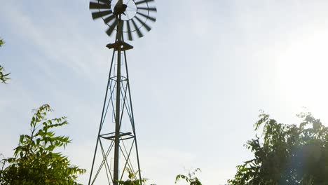 Slow-tilt-of-old-rusty-windmill-waterpump-on-farmland