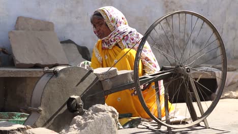 Indian-elderly-woman-cut-rocks-with-traditional-and-unusual-tool-wheel,-India