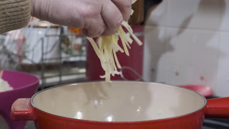 FONDUE---Throwing-shredded-cheese-onto-pot-for-preparation,-slow-motion