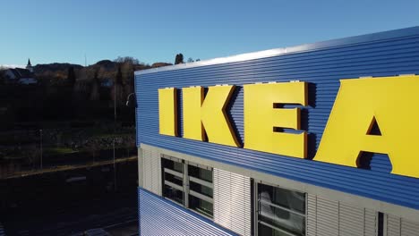 IKEA-logo-closeup---Slowly-backward-moving-aerial-close-to-Ikea-logo-on-warehouse---Sun-lighting-up-logo-and-warehouse-with-dark-background---Norway